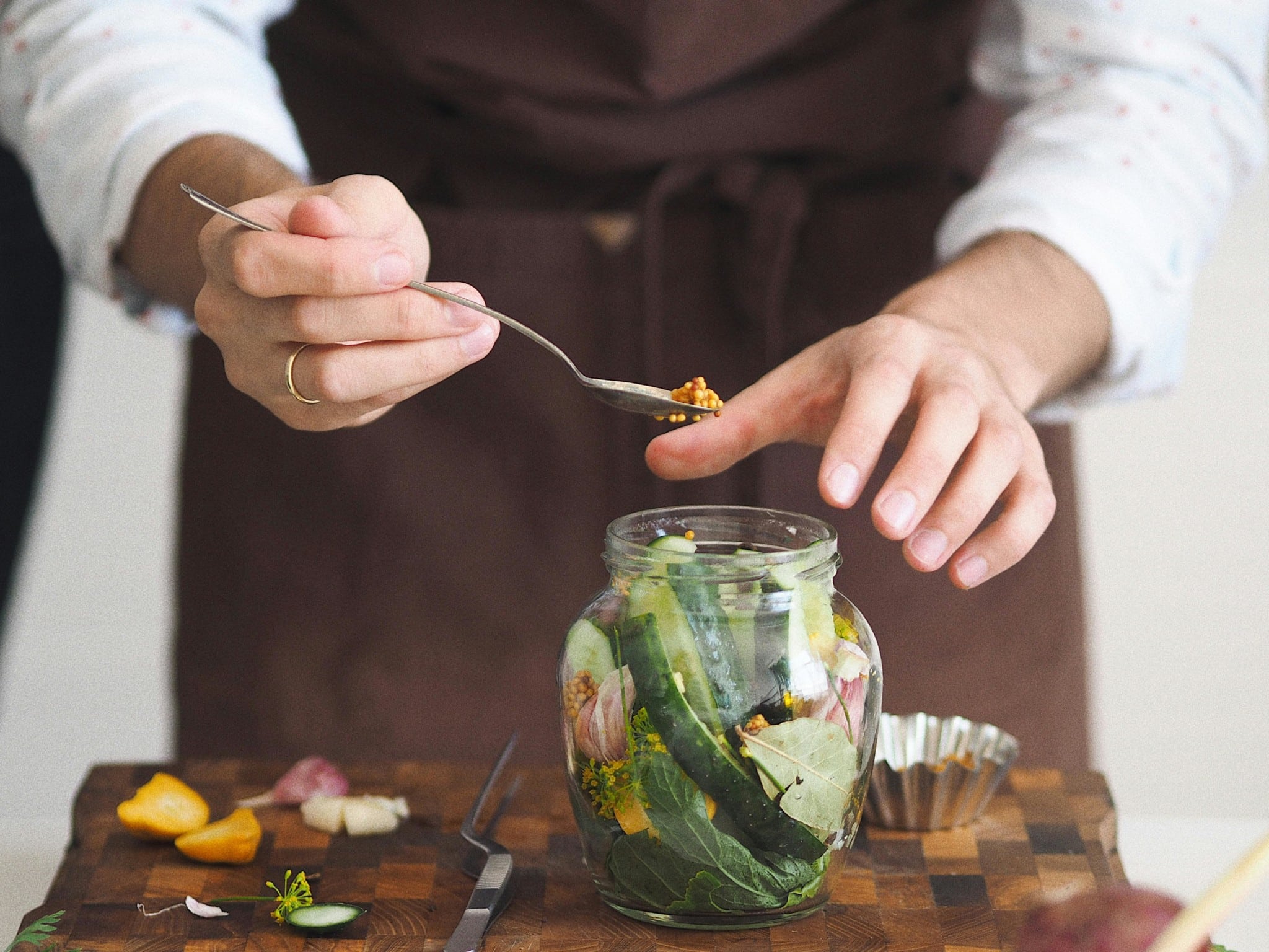 Un chef met de la moutarde dans un bocal de pickles